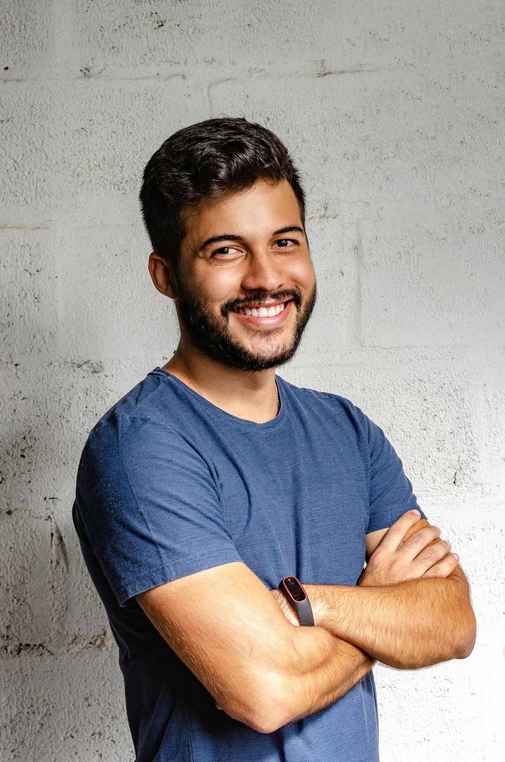 Smiling man with arms crossed against wall.